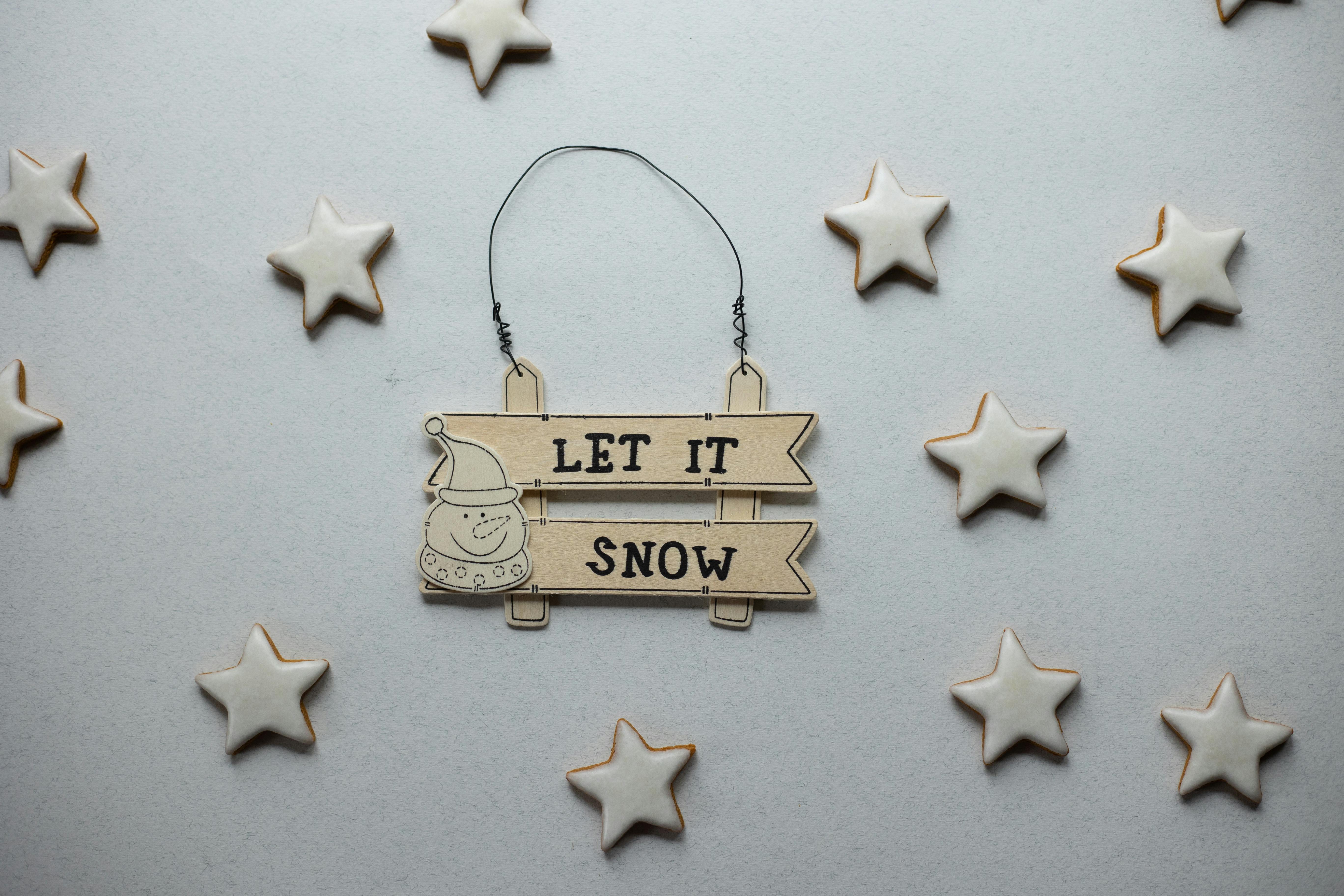 以冬天为主题的图像“让它雪”标志，由白色背景上的星状曲奇饼环绕