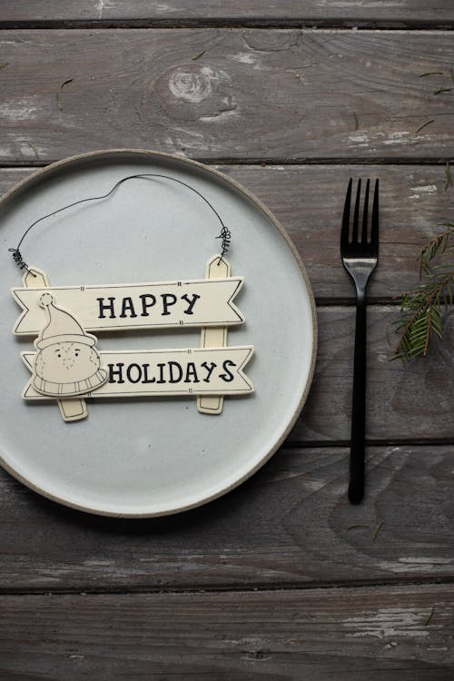 Plate with Happy Holidays Christmas decor served on table with fork