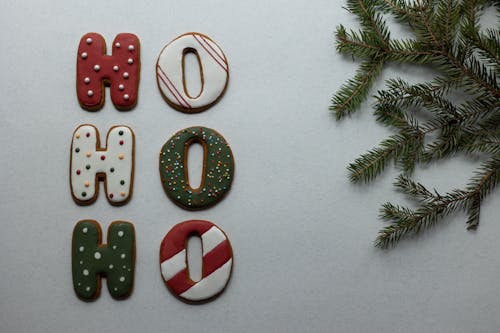 Traditional Christmas gingerbread letters arranged with fir twig on white surface
