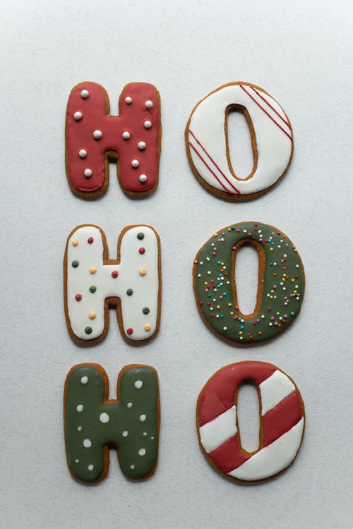 Traditional Christmas yummy gingerbread cookies in form of Ho Ho Ho letters decorated with icing and sprinkles and placed on white background