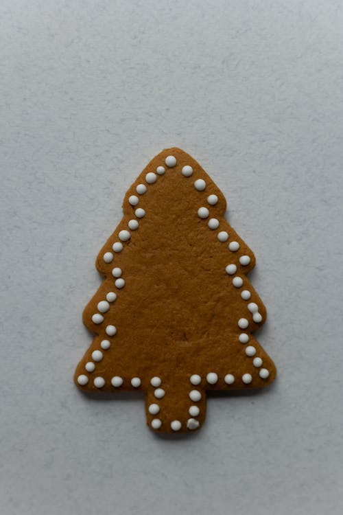 Top view of tasty aromatic biscuit in form of Christmas tree with sweet decor on gray background