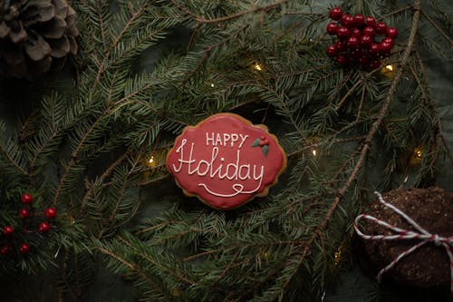 Happy Holiday inscription on biscuit on fir sprigs with garland