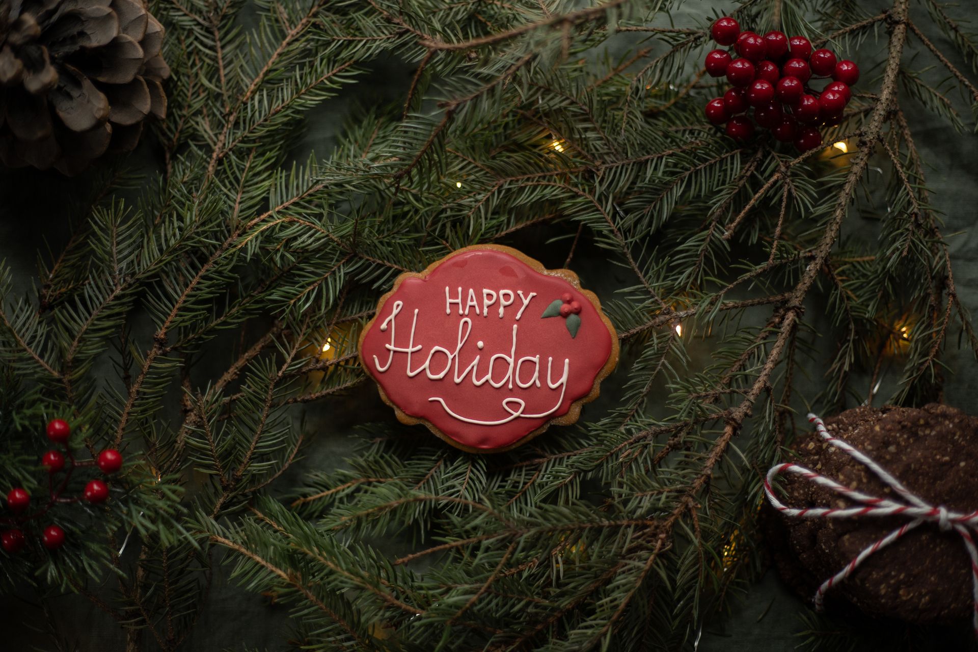 A decorative gingerbread cookie with 'Happy Holiday' text surrounded by festive pine branches and red berries.