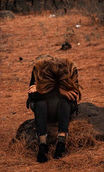 一个女人独自坐在森林中的岩石上，显得孤独而沉思