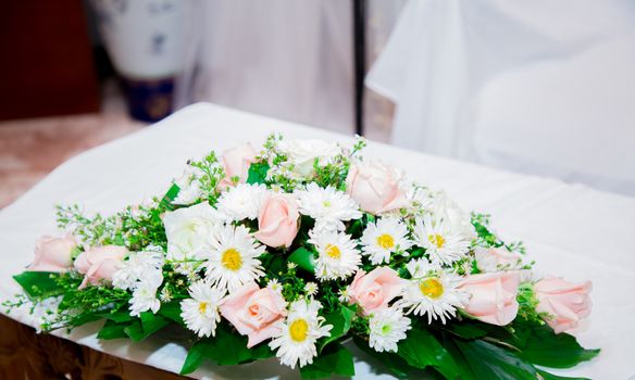 Beautiful bouquet of white daisies and pink roses on a white table setting, perfect for weddings.