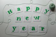 白色背景上，绿色毛毡字母拼出“新年快乐”