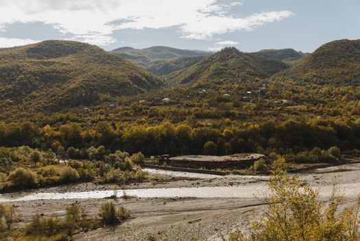 Peaceful countryside landscape with hills and river in autumn, showcasing vibrant natural beauty.