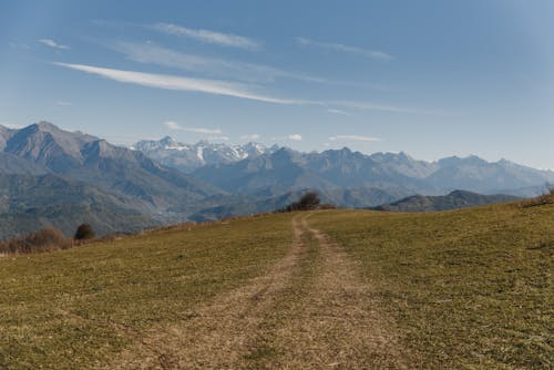 Lapangan Rumput Hijau Dekat Pegunungan Di Bawah Langit Biru