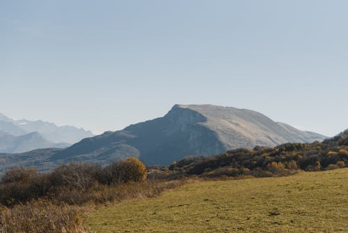 Lapangan Rumput Hijau Dekat Gunung Di Bawah Langit Putih