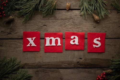 Xmas inscription on table surrounded by pine branches and cones