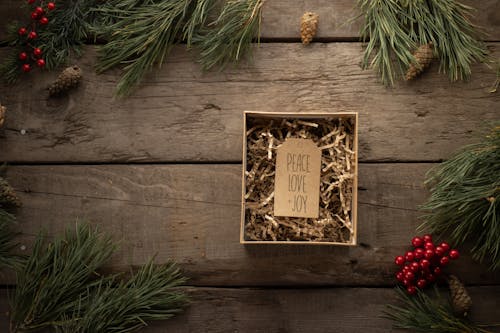 Tag with Christmas wishes on wooden table neat pine branches