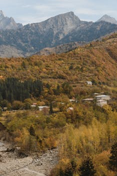 Explore serene mountain landscapes with charming villages nestled in vibrant autumn forests.