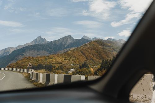 Free View of a mountain road with colorful autumn foliage through a car window, capturing a scenic travel experience. Stock Photo