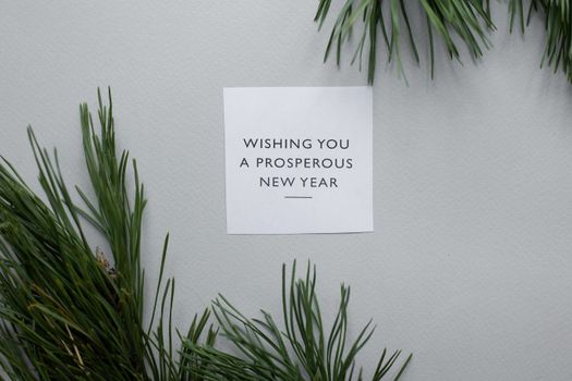 灰色背景上的针叶树枝旁，是一张简约的新年贺卡