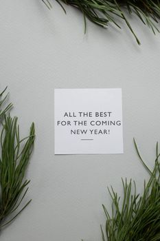 一张简约的新年贺卡上，松树小枝映衬在灰色背景中