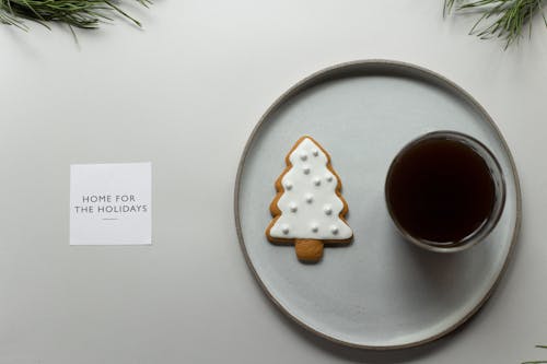 Free Layout of round plate with cup of coffee gingerbread cookie placed on gray background with Home for the holidays on postcard Stock Photo