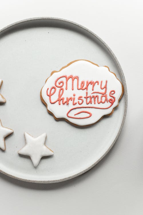 Handmade gingerbread cookie with wish Merry Christmas placed near star shaped cookies