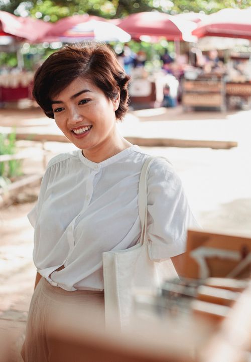 Free Cheerful young Asian female in stylish white blouse standing on street market on sunny day Stock Photo