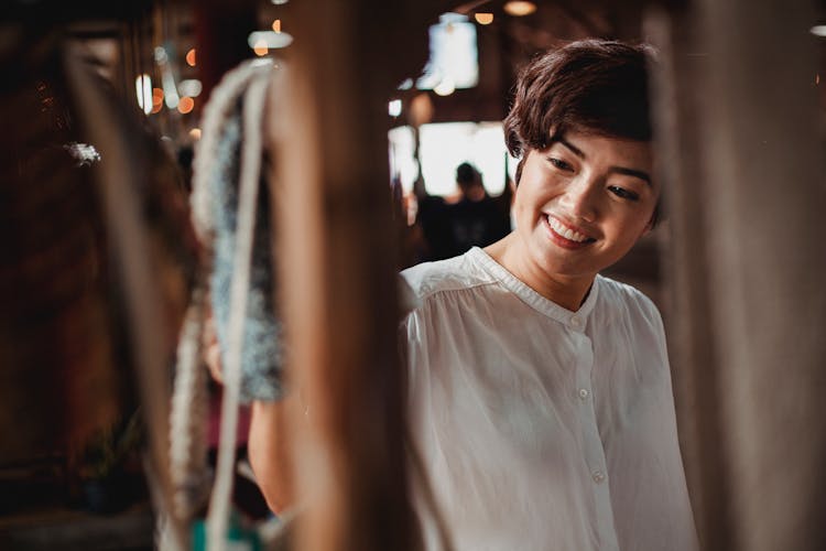 Crop Smiling Asian Woman Choosing Gift In Souvenir Market