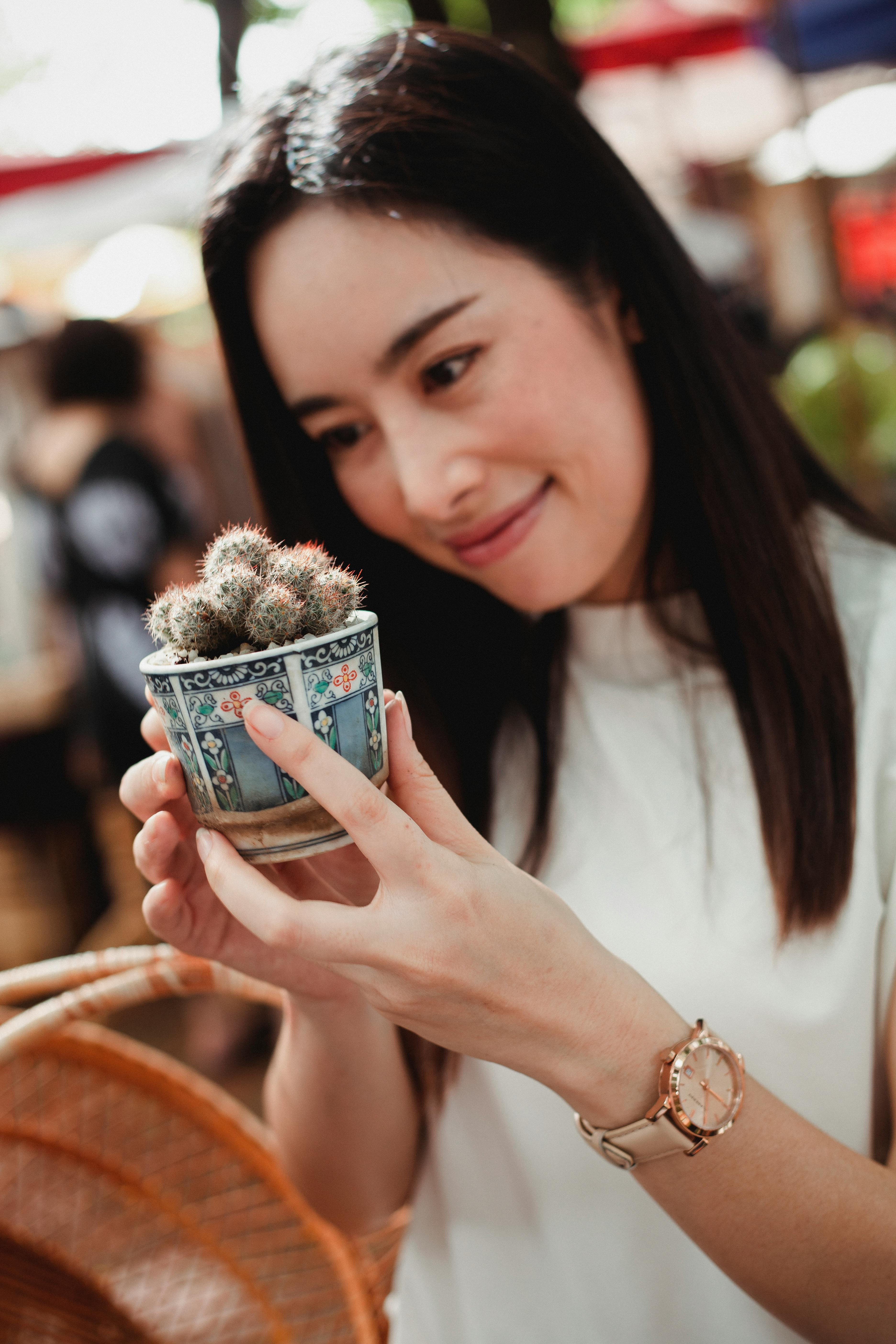 cheerful asian woman with small potted cactus in market