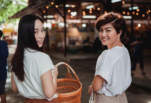 两个开朗的女人在阳光明媚的户外市场一起购物