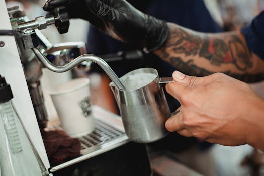 A barista expertly steams milk at a modern coffee shop counter.