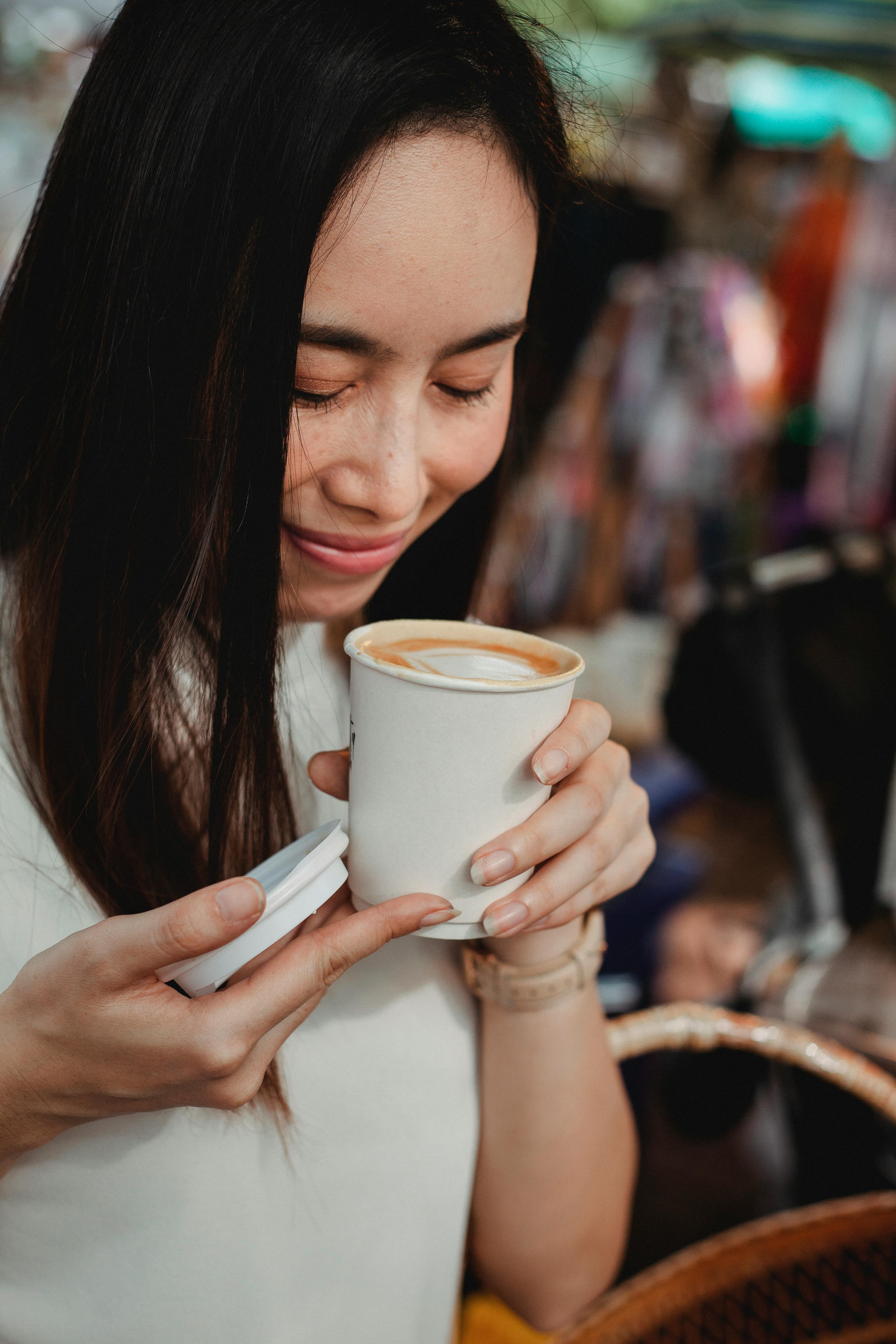 crop charming asian woman smelling freshly brewed cappuccino