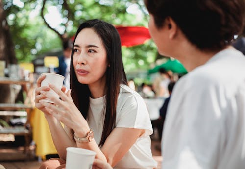 맑은 거리 시장에서 커피 브레이크를 갖는 긍정적 인 아시아 여성