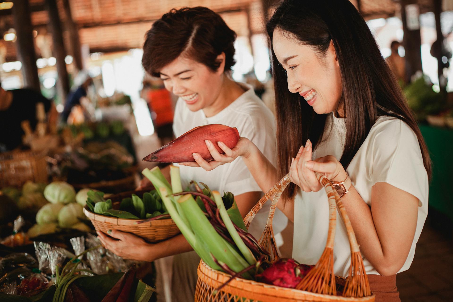 Asian women enjoying organic produce shopping at a lively local market, embracing fresh, healthy living.