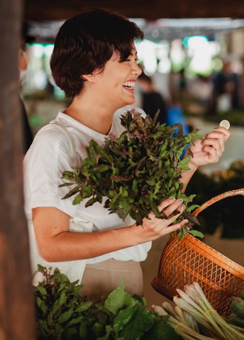 бесплатная Счастливый азиатский покупатель с пачкой лавровых листьев на рынке Стоковое фото