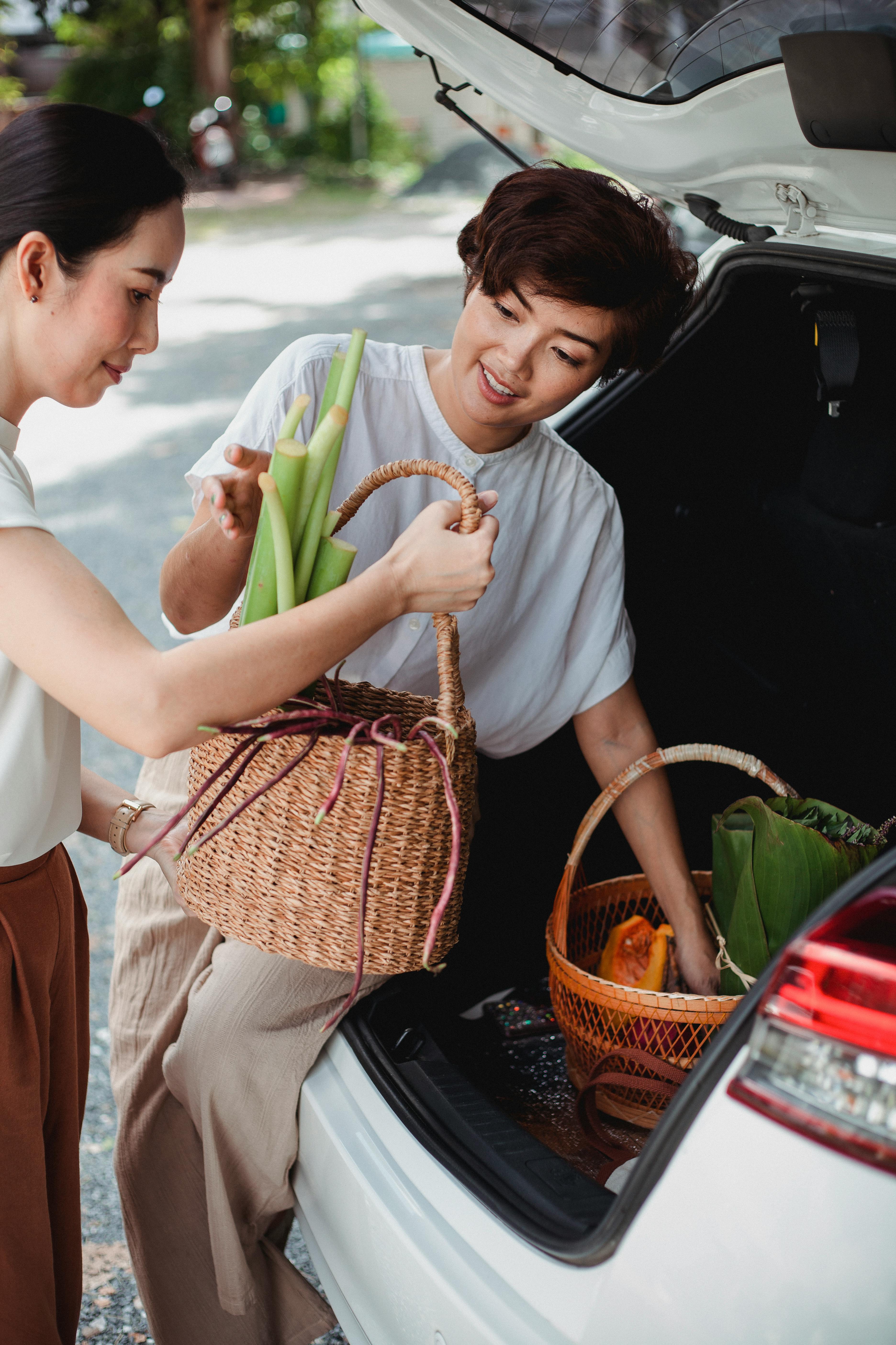 content asian girlfriends putting food baskets in trunk of car