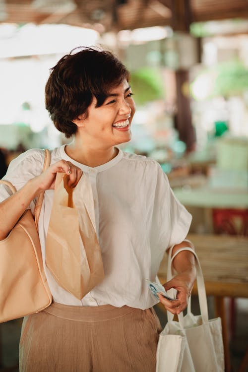 Free Positive Asian woman with food bag in market Stock Photo