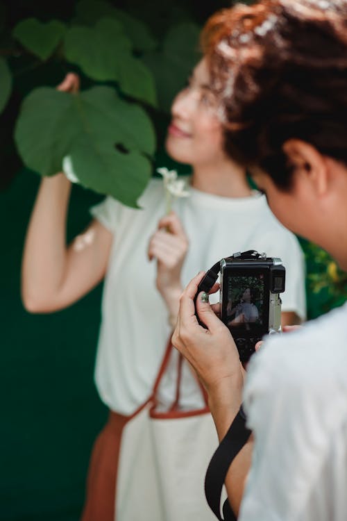 Урожай женщина, делающая фото улыбающейся азиатской подруги на камеру