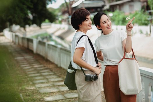 一位年轻快乐的民族女士用手指着靠近女友的相机，同时抬头望向路堤