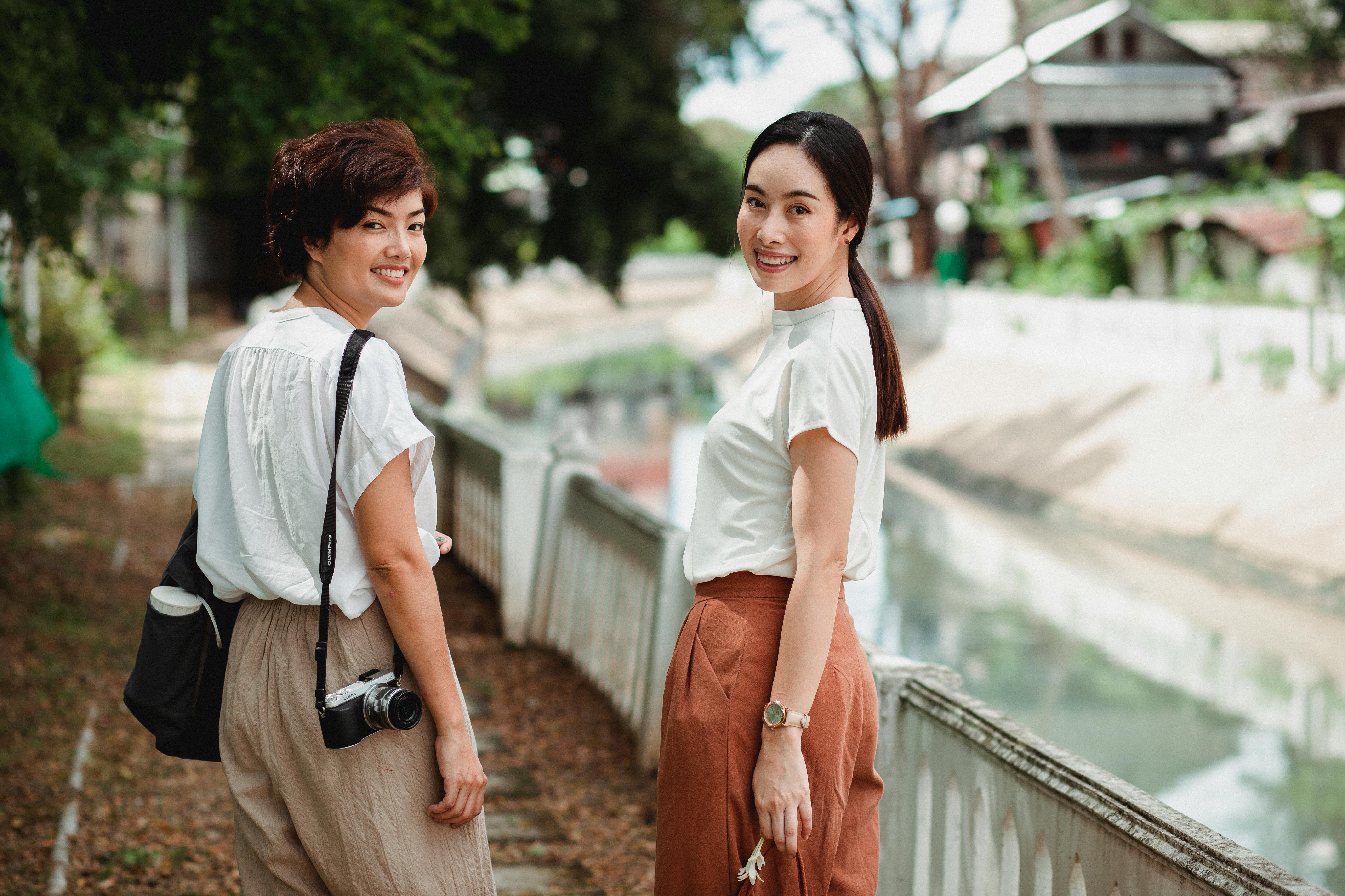 happy asian women on urban embankment near canal