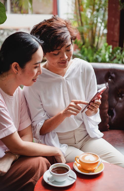 Calm Asian women looking at screen of smartphone