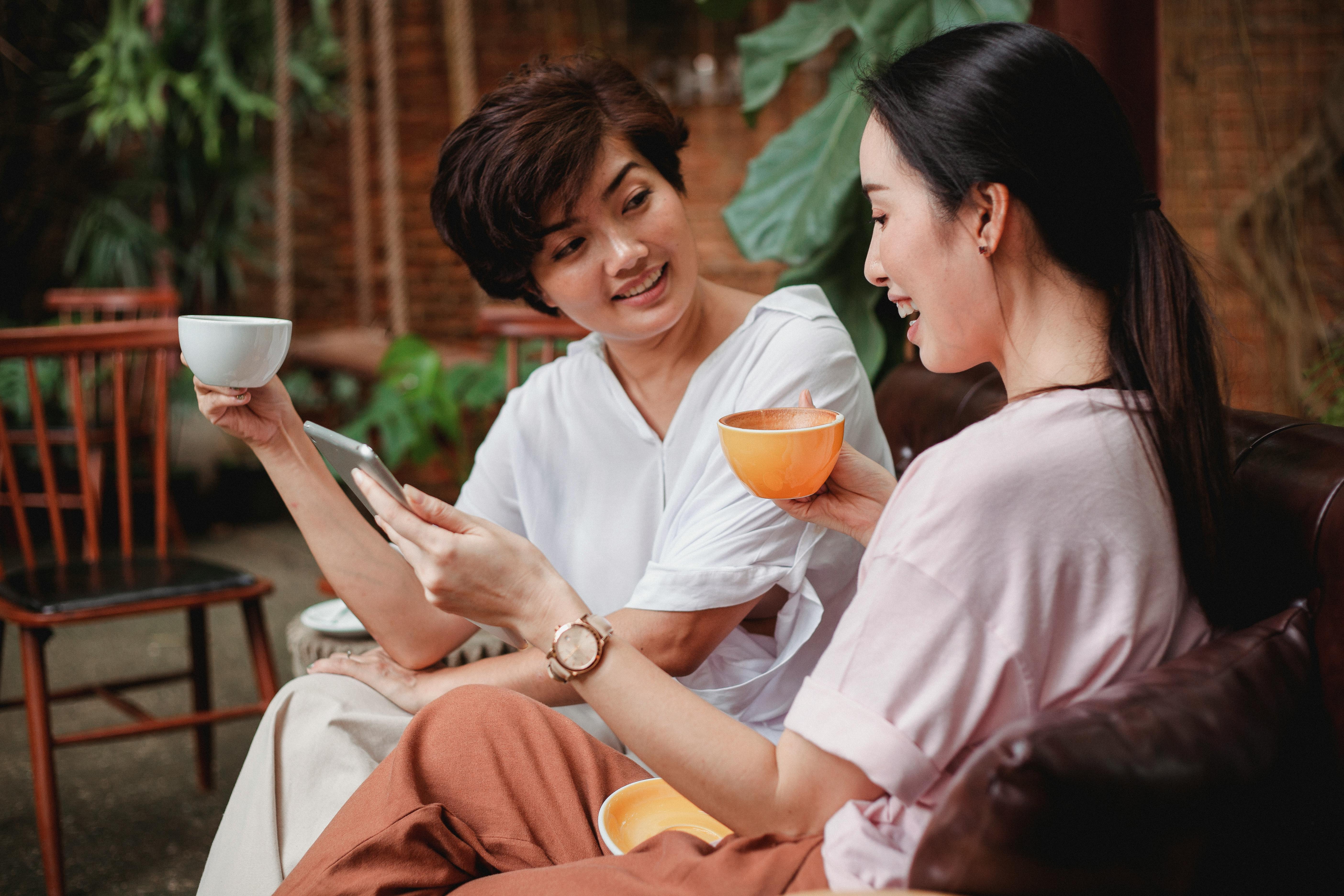 positive asian women drinking coffee in cafe