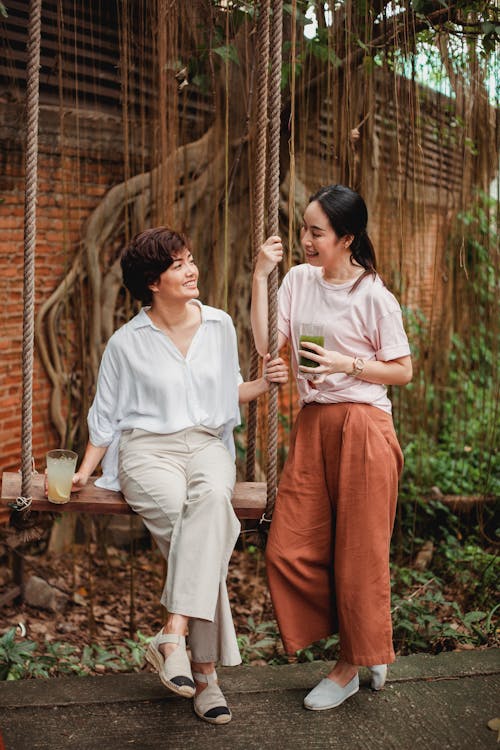 Sourire De Femmes Asiatiques Au Repos Dans Le Jardin Près Du Bâtiment