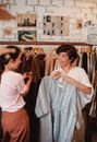年轻的民族女友在服装店挑选服装时，高兴地交谈并互相看着对方