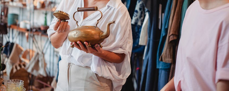 Crop anonymous female buyer holding Asian kettle with cover near partner in local shop