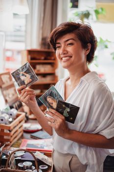 在舒适的商店环境中，一位开朗的女人展示了两张艺术卡片