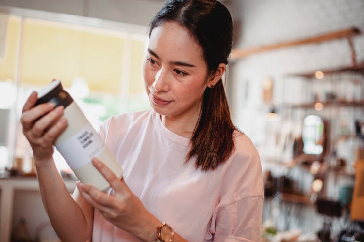 Crop Asian Female Buyer Watching Beauty Product In Shop