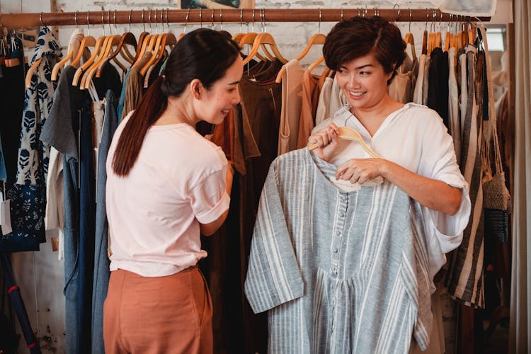 Glad Asian Shoppers Choosing Apparel In Clothing Store