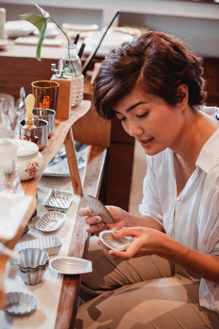 Asian Woman Selecting Molds For Pastry In Shop