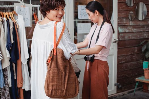 一对年轻的民族服饰购物者，带着织物袋，在街头商店挑选衣服