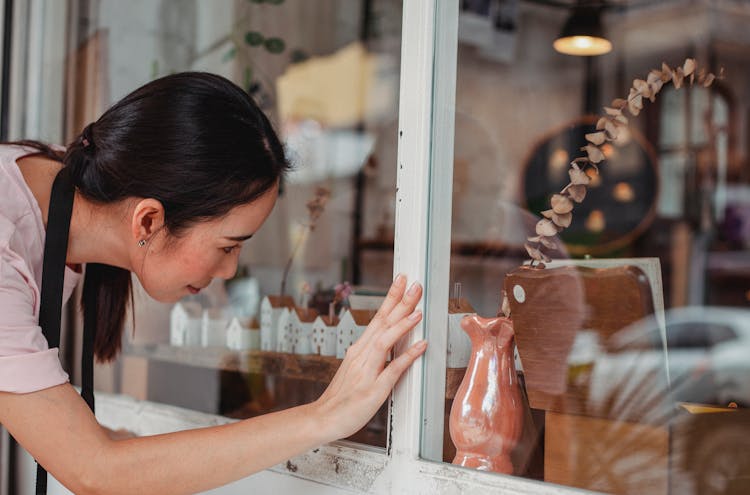 Asian Woman Touching Showcase Of Shop With Decorative Items