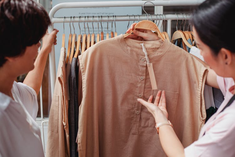 Crop Asian Shoppers Interacting While Choosing Clothes In Shop