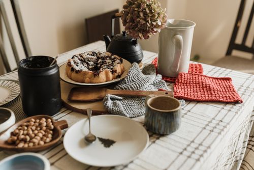 Free Inviting breakfast scene with a homemade cake, coffee, and cozy textiles on a kitchen table. Stock Photo