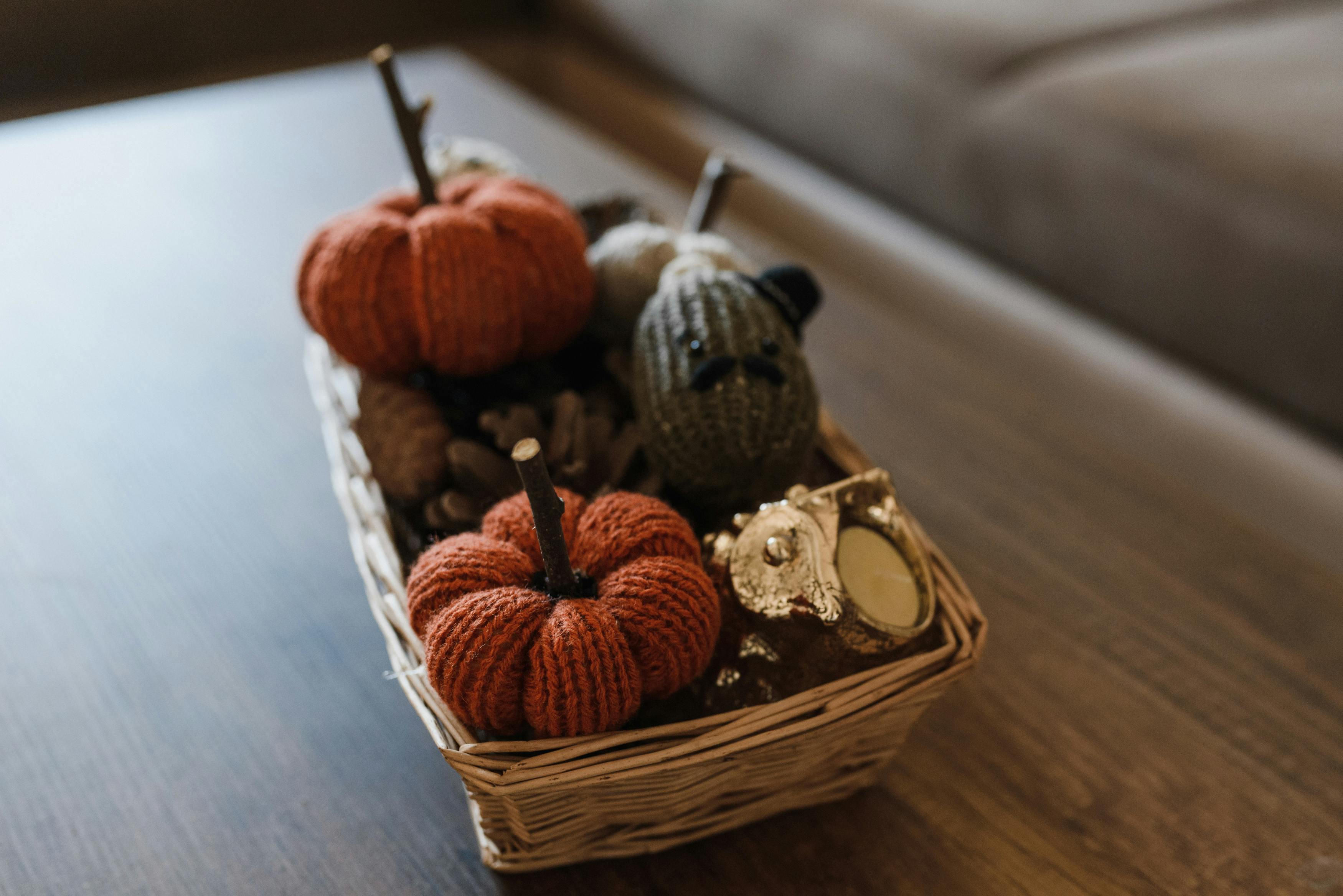 Warm autumn decorations featuring knitted pumpkins in a wicker basket.