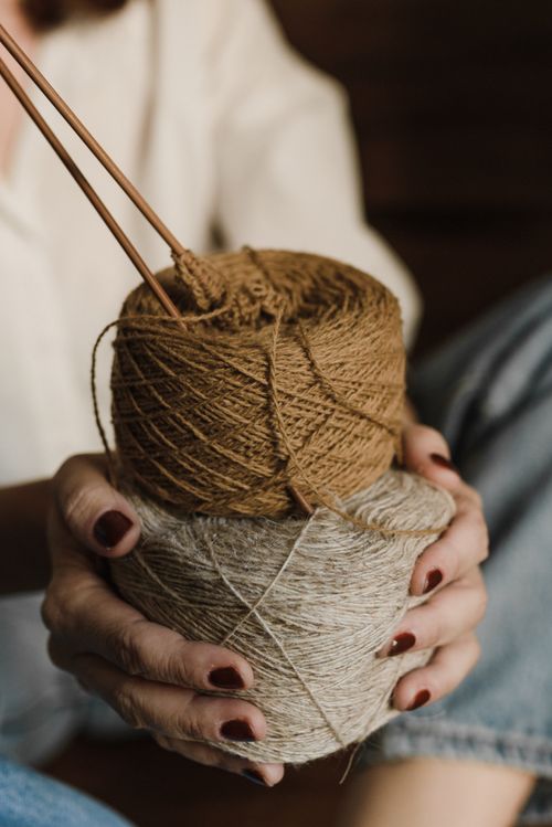 Free A close-up shot of hands holding balls of brown and tan yarn with knitting needles, emphasizing a cozy and creative atmosphere. Stock Photo